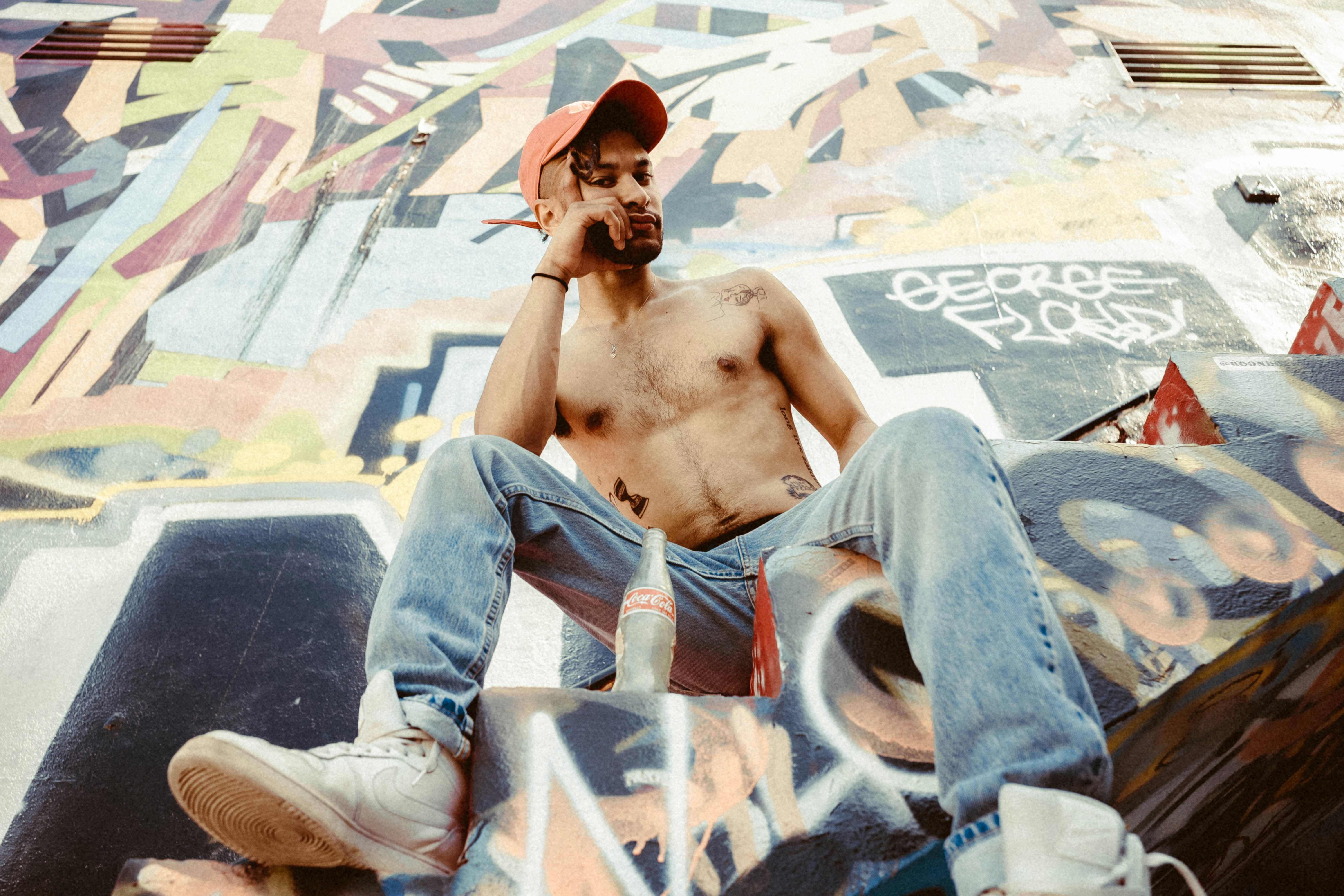 topless man in blue denim jeans sitting on white plastic chair